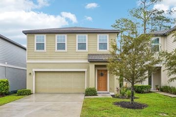 Deland apartment for rent - A beige house with a brown door and a tree in front.