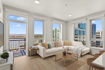 Vancouver apartment for rent - A living room with a white couch and a balcony with a view of the city.