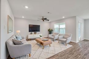 Ocean Springs apartment for rent - A living room with a grey sofa, a wooden coffee table, and a ceiling fan.