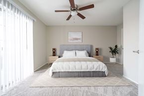 Olathe apartment for rent - A bedroom with a large bed and a ceiling fan.