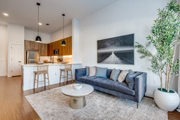 Dallas apartment for rent - A modern living room with a grey sofa, a coffee table, and a large painting on the wall.