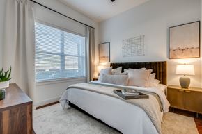 Dallas apartment for rent - One-Bedroom Apartments in Old East Dallas, TX - 4600 Ross - Bedroom Features A Neatly Made Bed, Soft Neutral Decor, Bedside Lamps, And Framed Wall Art.