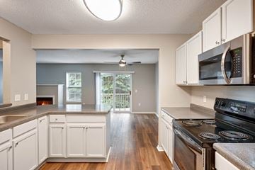 Burnsville townhouse for rent - A kitchen with white cabinets and a black stove top oven.