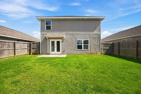 Foley apartment for rent - A house with a grey exterior and a white door is surrounded by a green lawn.