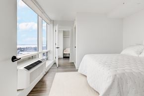 New Rochelle apartment for rent - A bedroom with a large bed and a window with a view of the city.