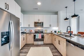 Hutto apartment for rent - A modern kitchen with a refrigerator on the left and a stove top oven in the middle.