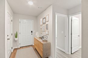 Pensacola apartment for rent - A hallway with a white door, a wooden bench, and a wall with pictures and a clock.