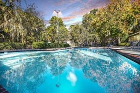 Savannah apartment for rent - Greentree Apartments in Savannah, GA photo of a swimming pool with trees in the background and a cloudy sky