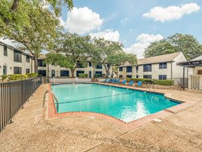 San Antonio apartment for rent - A swimming pool surrounded by a fence and chairs.
