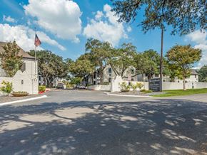 San Antonio apartment for rent - A sunny day at the entrance of a residential area with a flag flying in the background.