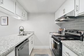 Phoenix apartment for rent - One Bedroom Apartments in North Mountain Village, Phoenix, AZ - Ardella on 28th - Kitchen with Wood-Style Flooring, Granite Countertops, Stainless Steel Appliances, and White Cabinetry.