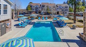 Flagstaff apartment for rent - A large swimming pool surrounded by blue lounge chairs and umbrellas.