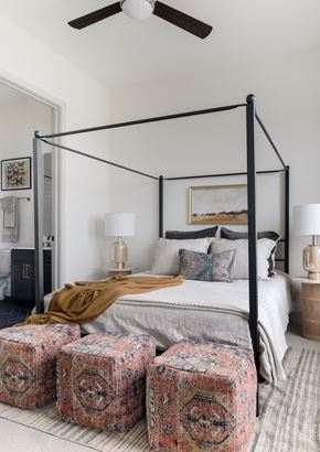 Dallas apartment for rent - Luxury Apartments In Uptown, Dallas, TX - Katy Trail Uptown - A Bedroom With Neutral Bedding, Two Matching Bedside Tables, Glass-Based Lamps, Framed Landscape Painting, And A Neutral Palette Rug.