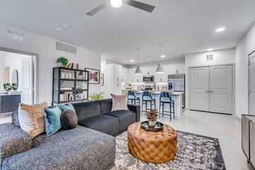 Austin apartment for rent - A modern living room with a black couch and a round ottoman.