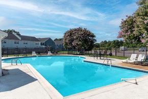 Newport News apartment for rent - A large swimming pool surrounded by a fence and trees.