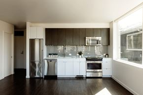 Seattle apartment for rent - 2-Bedroom Apartments in Eastlake, WA - Shelton Eastlake - Kitchen With Dark, Wood-Grain Upper Cabinetry, Tile Backsplash, Stainless Steel Appliances, And Wood Flooring.