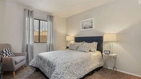 Mesa apartment for rent - Apartments in Mesa, AZ - Mesa Station - Bedroom with Large Bed, Window with Curtains, Round Bedside Tables, ,Armchair and Carpeted Flooring.