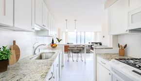 Washington apartment for rent - A kitchen with white cabinets and a marble countertop.