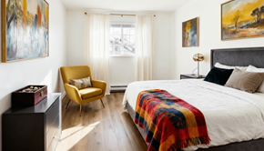 Everett apartment for rent - Twin Creek, Everett, WA, Apartments For Rent - Woodbrook - Bedroom With Vinyl Plank Flooring, Large Bed, Dresser, Armchair, Nightstand with Lamp, Insulated Windows, and Window Coverings.