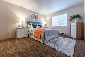 Kent apartment for rent - Kent, WA, Pet-Friendly Apartments - Berkeley Heights - Bedroom with Full-Sized Bed and Nightstands, also with Vaulted Ceilings and White Faux-Sheepskin Rug Layered Over a Dark Brown Carpet.