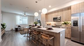 Phoenix apartment for rent - Fully Furnished Townhomes in North Phoenix, AZ - Bloom at Deer Valley - Kitchen With Wood Cabinets, Stainless Steel Appliances, White Island Countertop, Bar Seating, and Pendant Lights.