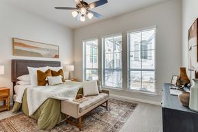 Fate apartment for rent - A bedroom with a bed, a bench, and a ceiling fan.