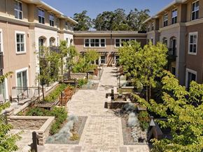 Novato apartment for rent - Apartments in Novato, CA, with In-Unit Washer and Dryer - Millworks - Courtyard With Paved Walkways, Garden Beds, Benches, Trees, Balconies, And Surrounding Apartment Buildings.