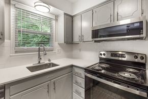 Raleigh apartment for rent - a kitchen with white cabinets and a sink and a stove