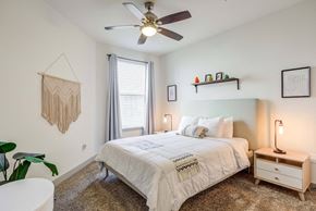 Nashville apartment for rent - Bright, modern bedroom with queen bed, macrame wall hanging, and ceiling fan.