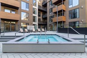 Oakland apartment for rent - a pool with chairs in front of an apartment building