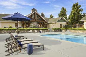 Coeur D Alene apartment for rent - A pool with sun loungers and a blue umbrella in front of a house.