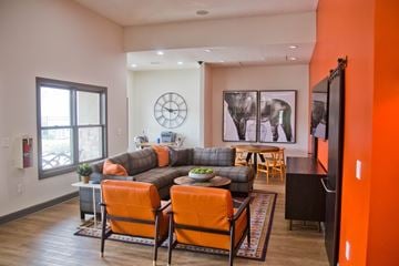 Raymore apartment for rent - A living room with a grey couch and orange chairs.