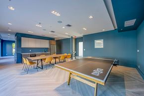 Miami apartment for rent - Modern recreation room with a ping pong table, long dining table, and kitchen area.