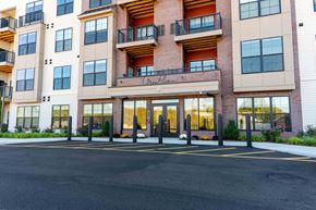 Fairfield apartment for rent - Front entrance of Creekline at Fairfield apartments in Fairfield, CT featuring a modern brick-and-siding exterior, glass entry doors, and balcony residences above.