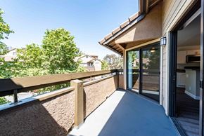 Rancho Cucamonga apartment for rent - A balcony with a wooden railing and glass doors leading to a home interior.