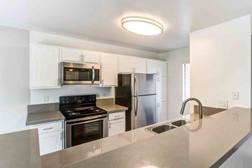 Rancho Cucamonga apartment for rent - A kitchen with white cabinets and stainless steel appliances.