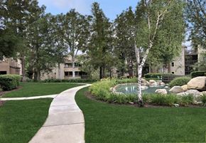 Rancho Cucamonga apartment for rent - A walkway leads through a landscaped area with a pond and rocks.