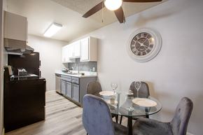 Tucson apartment for rent - Apartments for Rent in Tucson, AZ - Peaks at Redington - Dining Area with Wood-Style Flooring, Glass-Top Table, Chairs, Ceiling Fan, and View of Kitchen.