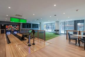 New Rochelle apartment for rent - The bowling alley amenity space at Encore 325 Apartments features glossy wood lanes, a green turf area for games, and large windows with natural light.