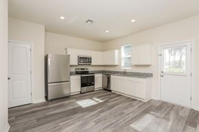 Deland townhouse for rent - A kitchen with a refrigerator, microwave, oven, and sink.