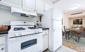 Washington apartment for rent - A white stove and refrigerator in a kitchen with a table and chairs in the background.