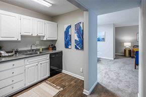 Raleigh apartment for rent - A kitchen with white cabinets and a blue painting on the wall.
