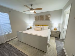 Hattiesburg apartment for rent - Pet-friendly Twin Oaks Apartments bedroom with large bed, ceiling fan, and window with white curtains in Hattiesburg, MS