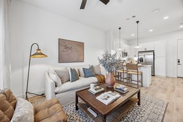 Mckinney apartment for rent - A living room with a brown leather chair and a white couch with blue and orange pillows.