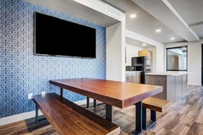 Phoenix apartment for rent - Studio Apartments in Phoenix, AZ - Imperial - Community Space with Wood-Style Flooring, Picnic-Style Table and Benches, Wall-Mounted TV, Kitchen, and Window.