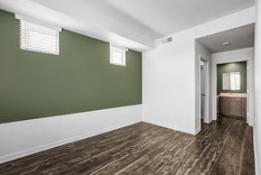 Phoenix apartment for rent - Apartments in Downtown Phoenix, AZ - Imperial Apartments - Spacious Empty Bedroom with Wood-Style Flooring, Green Accent Wall with Windows, and Access to Oversized Closet and Bathroom.