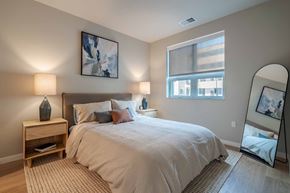 Kenosha apartment for rent - A bedroom with a large bed, a nightstand with a lamp, and a painting on the wall.