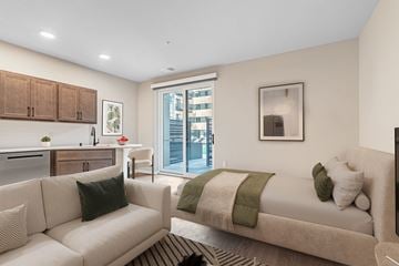 Kenosha apartment for rent - A modern living room with a couch, a bed, and a kitchen area.