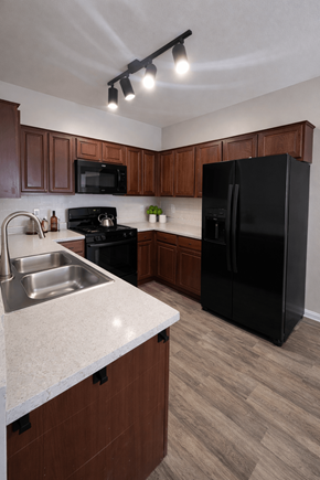 Las Vegas apartment for rent - A kitchen with a black refrigerator and brown cabinets.
