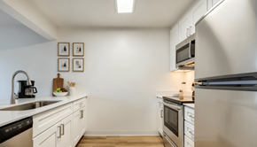 Everett apartment for rent - Everett, Washington, Apartments - Woodbrook - Kitchen With Stainless Steel Appliances, Vinyl Plank Flooring, Quartz Countertops, White Cabinets, And A Breakfast Bar.